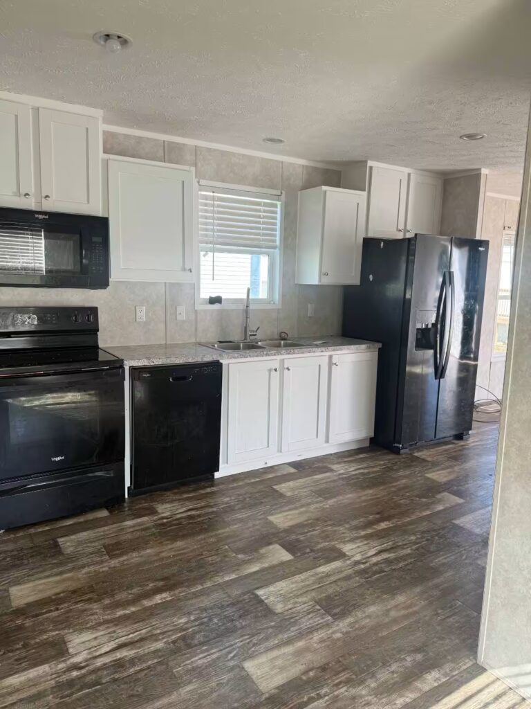 Kitchen with white cabinets, black appliances, and wood-look flooring.